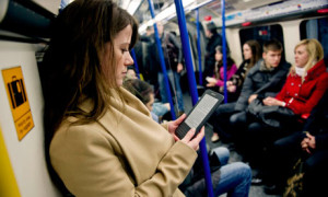A woman reading a Kindle ebook on a London bus. Amazon says downloads have overtaken print sales